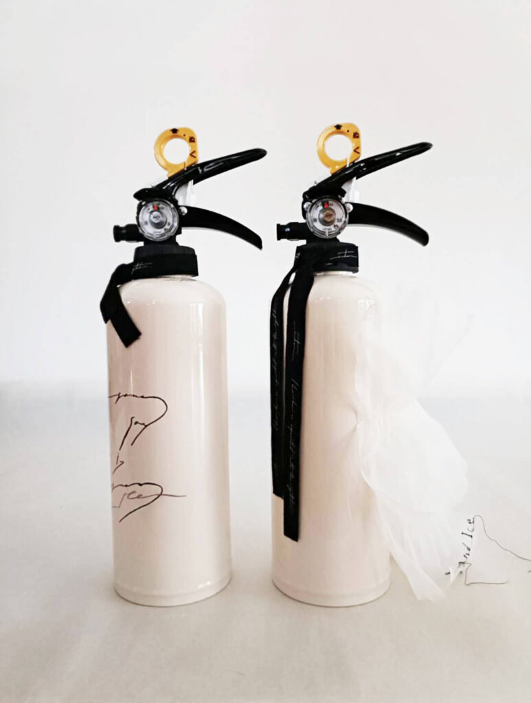 白い消火器2本正面。リボンや文字入りデザインが施されている。