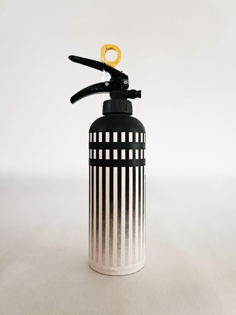 消火器背面。正面から続く縦ストライプデザインの白黒グラデーション。